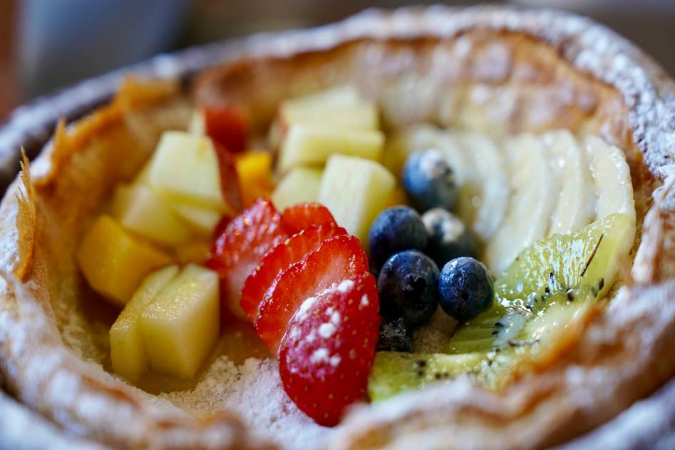 Wooden table with fresh berries, avocado mousse, and herbal tea
